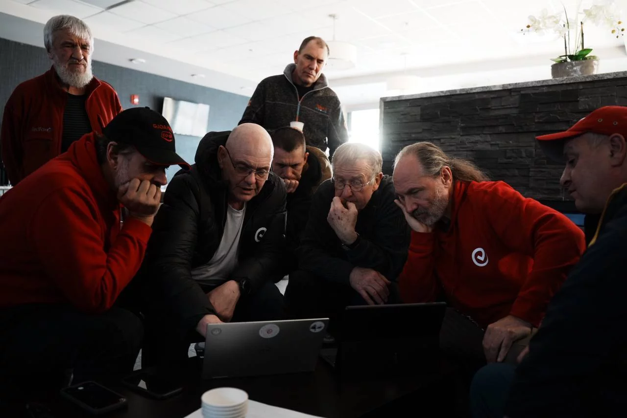A group of people gather around a laptop